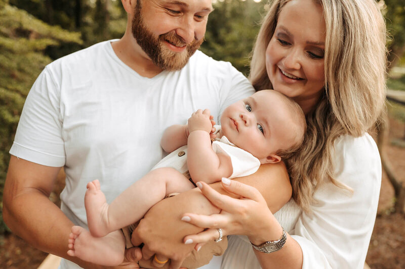 Charlotte family of four sharing sweet smiles and cuddles during a candid photography session.