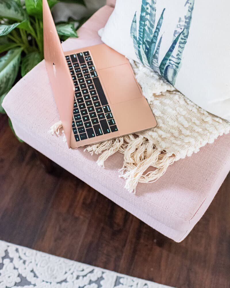 Pink laptop on a pink chair with a pillow