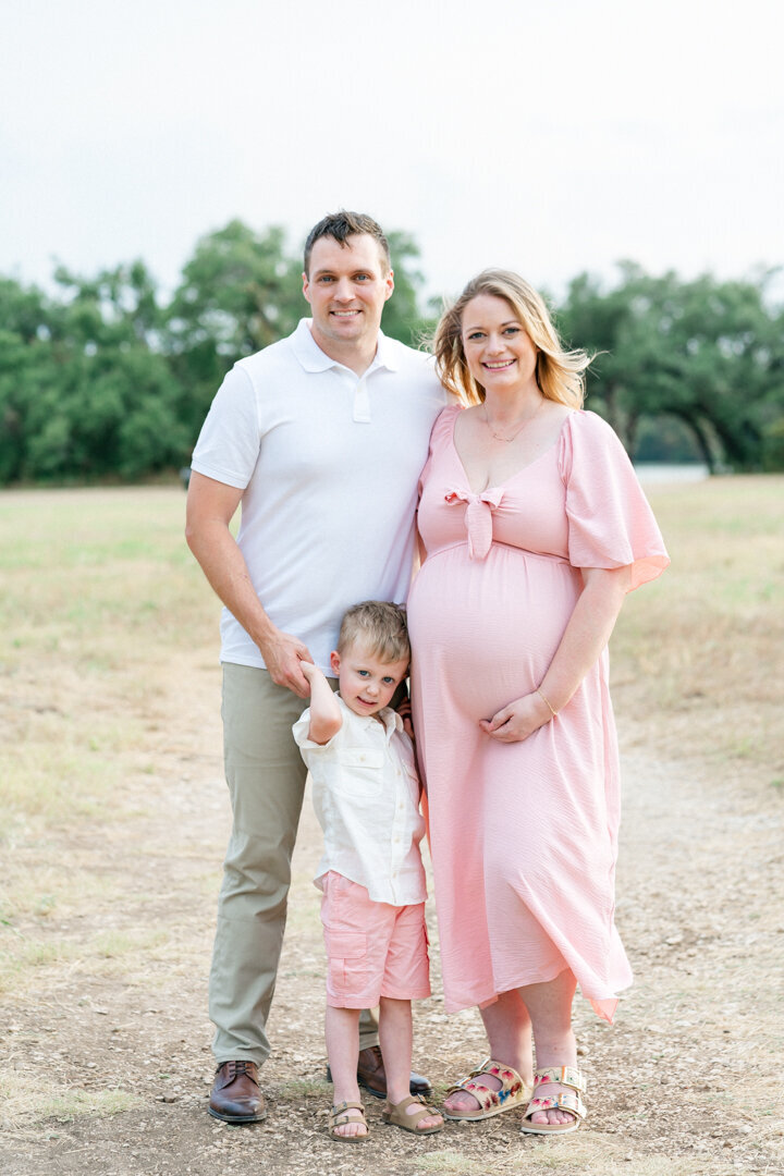 A family stands on a path at Brushy Creek Lake Park and look at their Cedar Park photographer's camera.