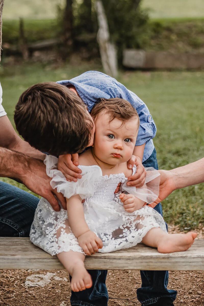 Brother kissing little sister on cheek during family session in New Braunfels, TX.