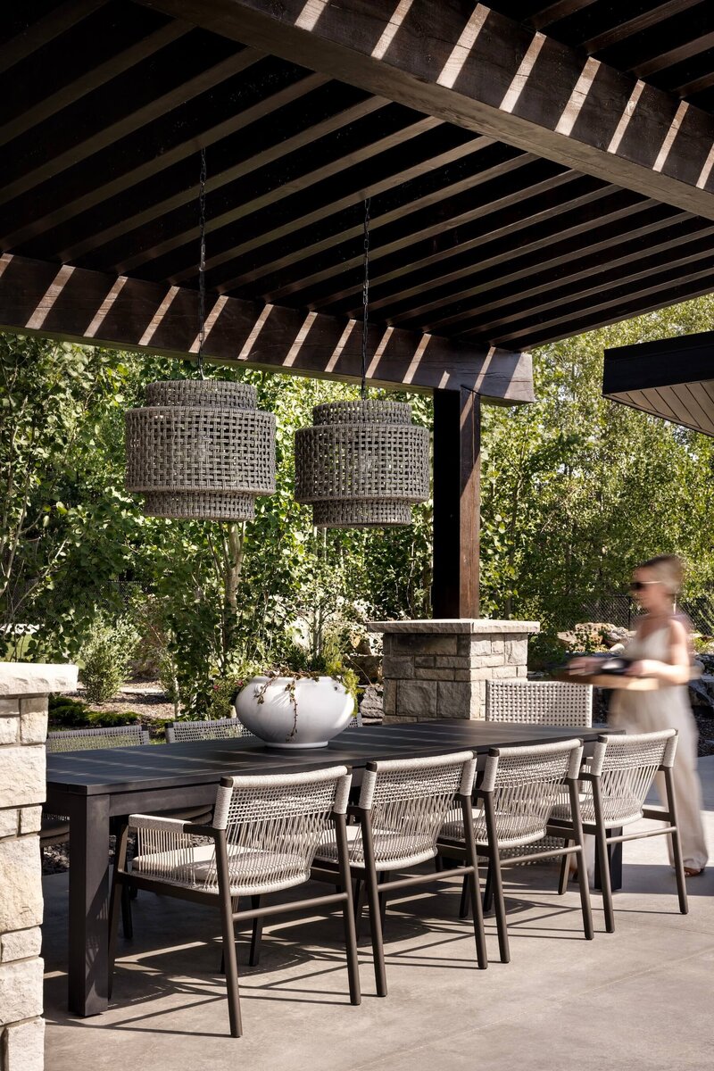 Outdoor dining space with rattan dining fixture, large outdoor table and chairs with a custom built pergola. 