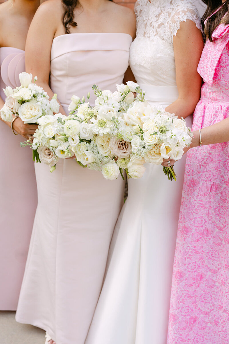 bridesmaids in pink dresses holding floral bouquets with the bride