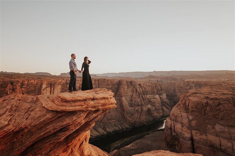 A couple standing a the edge of a red rock cliff