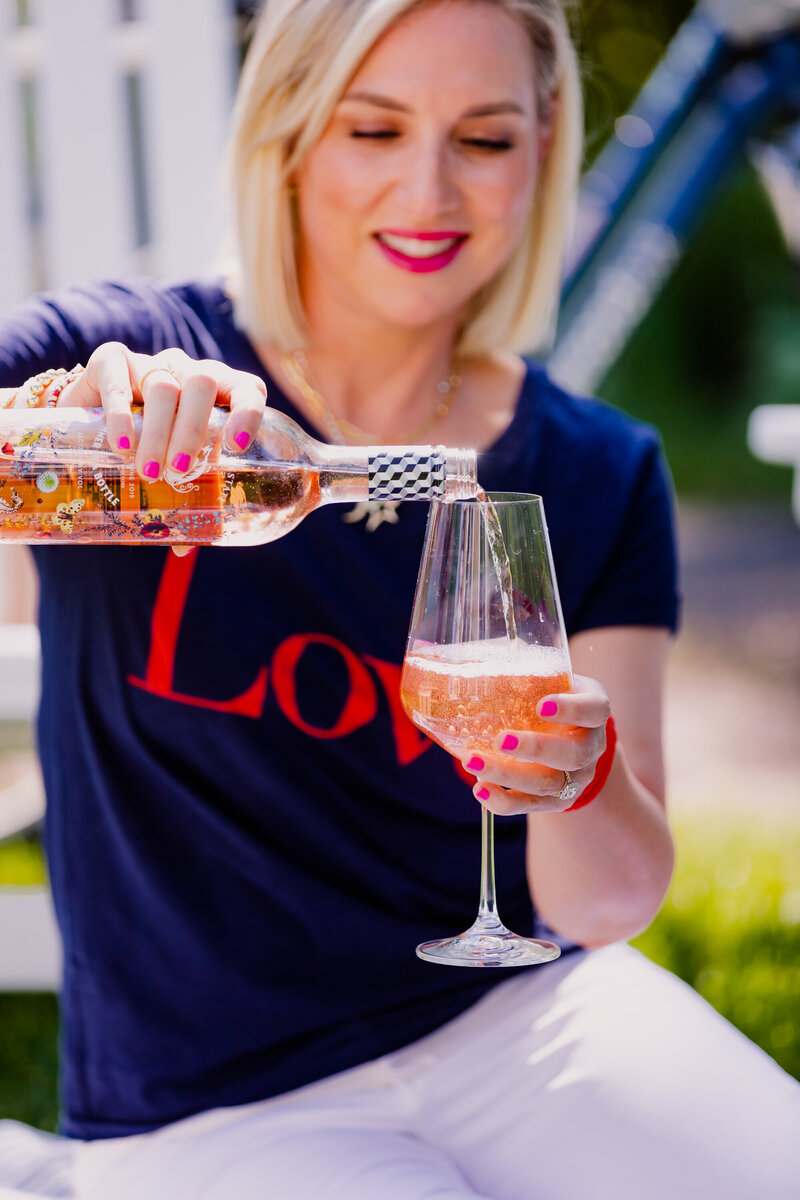 Jessi Cabaninpour champaign in a glass with a blue love shirt on.