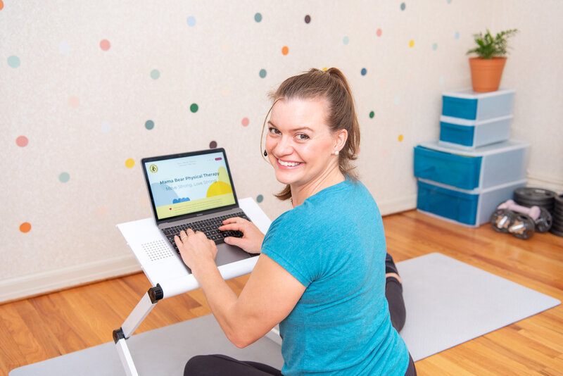 A female physical therapist smiling and showing her website on her laptop.