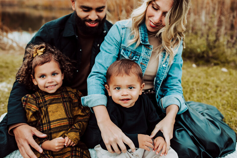 family sitting down, denim  jackets, black shirt, plaid dress, smiles, happy kids, little brother, older sister, curly hair,