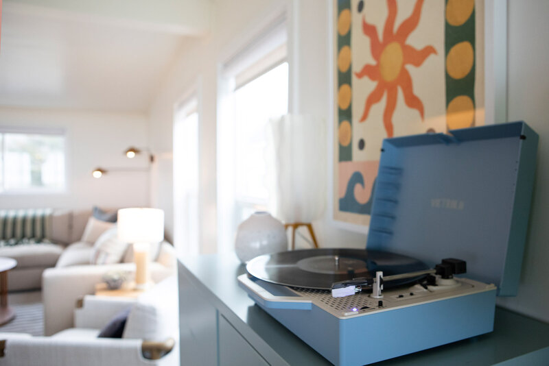 Details from a short term rental renovation featuring a blue record player and sun-themed art print on the wall.