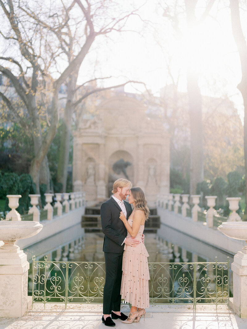 a couple standing in front of a fountain in paris