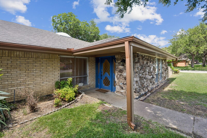 Charming stone-front duplex shaded by a mature tree, featuring two covered entryways and separate driveways—ideal for multi-family living or investment potential.