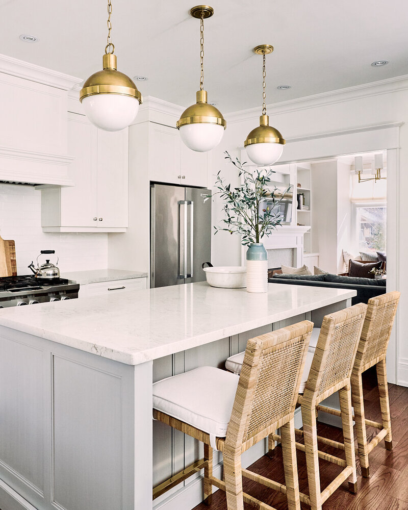 coastal kitchen with grey island cane counter stools and gold pendant lights