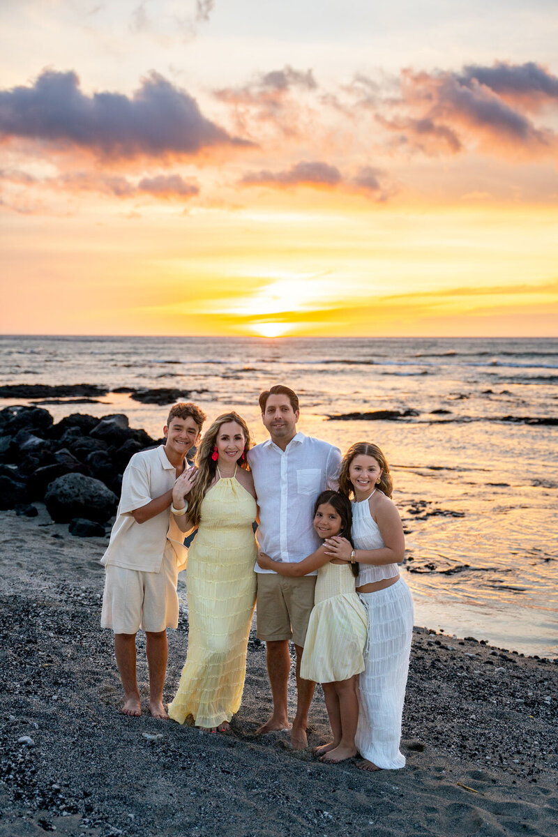 Family smiling at sunset on a black sand beach on the Big Island, by Hawaii Adventure Portraits