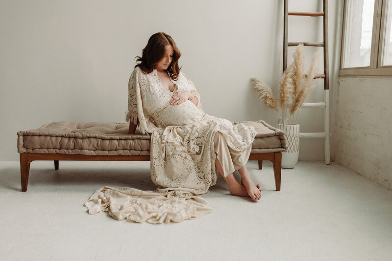 maternity session in a natural light studio with mom wearing a lace gown 