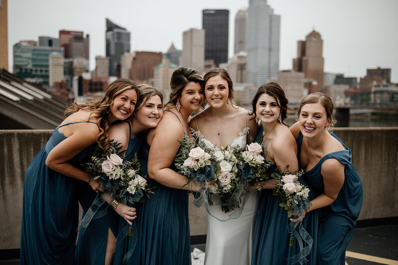 bride and bridesmaids holding eachother on the rooftop