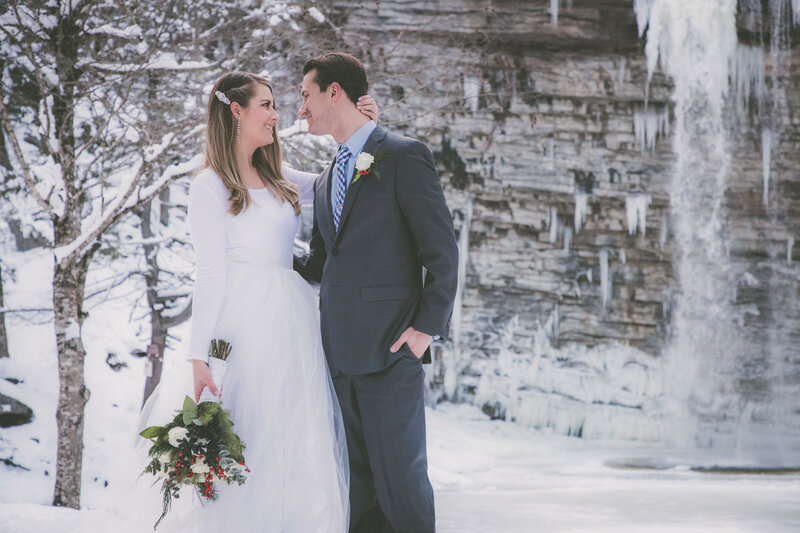 Newlyweds look at each other and pose for the camera during their winter adventure elopement.