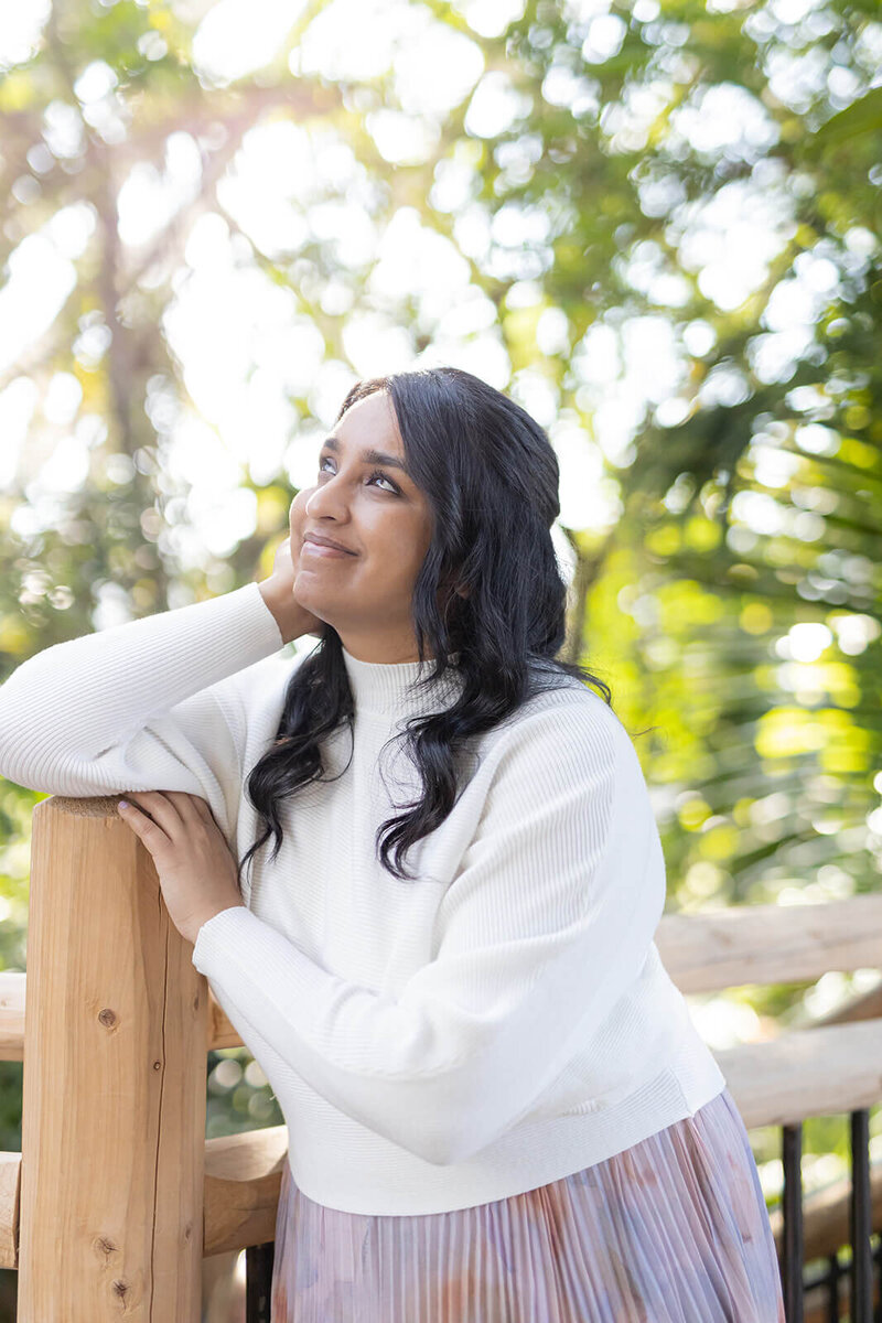 Indian girl posing for a portrait at the Botanic Garden in Denver CO. She is looking romantically up, sunlight is coming from the windows behind her. 