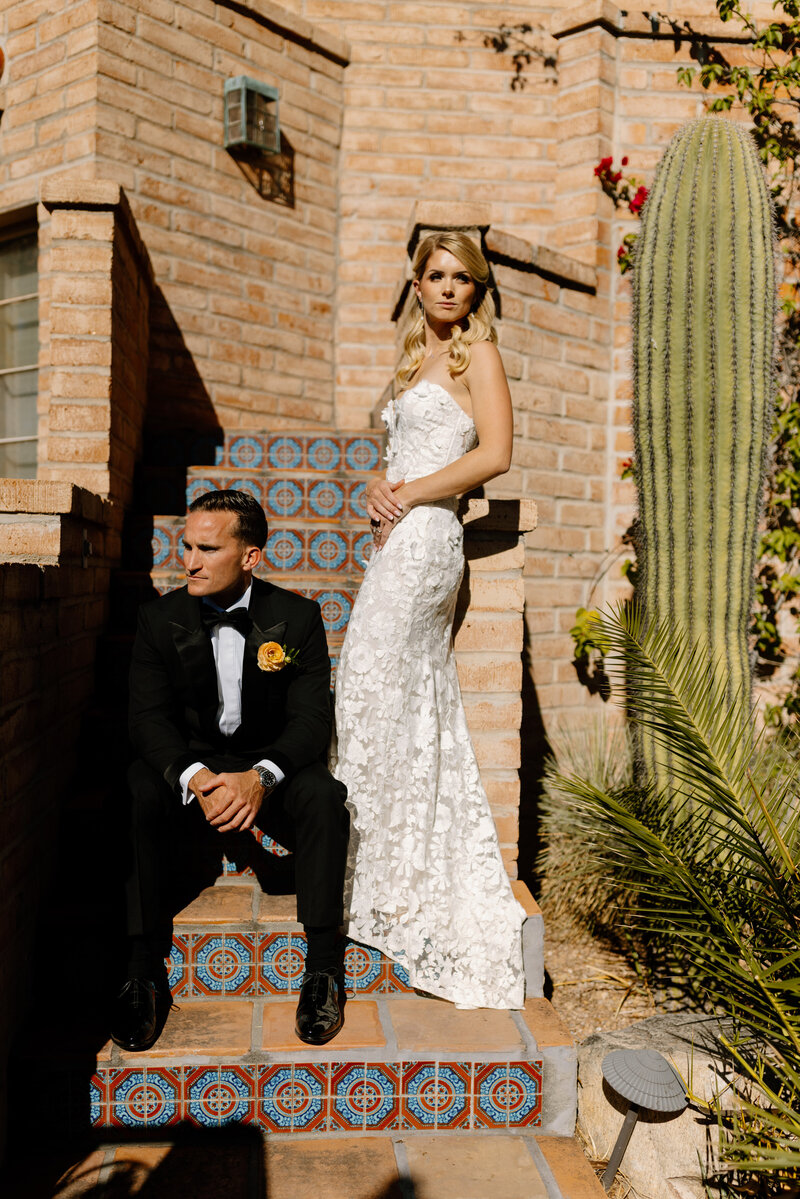 A wedded couple stand in a desert field at sunset during their backyard wedding in Tucson, Arizona.
