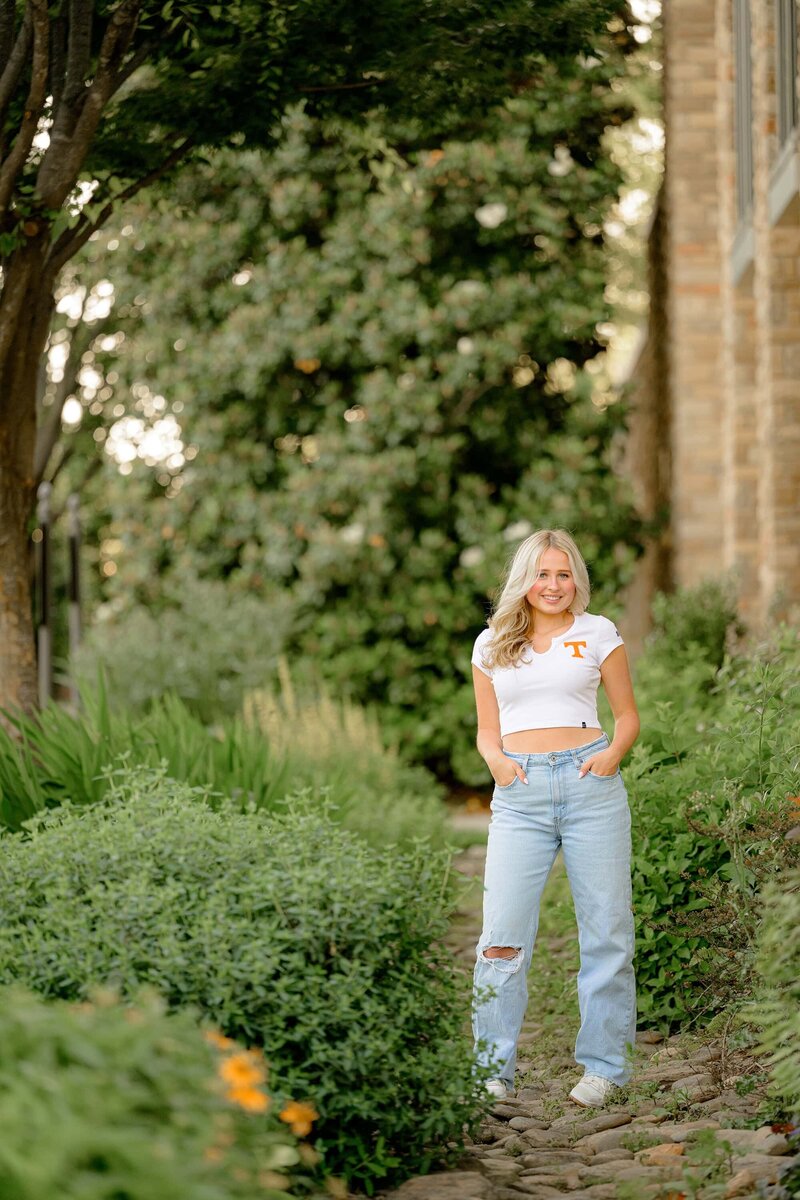 senior photo of a blonde graduate standing on rocks wearing jeans and a UT crop top