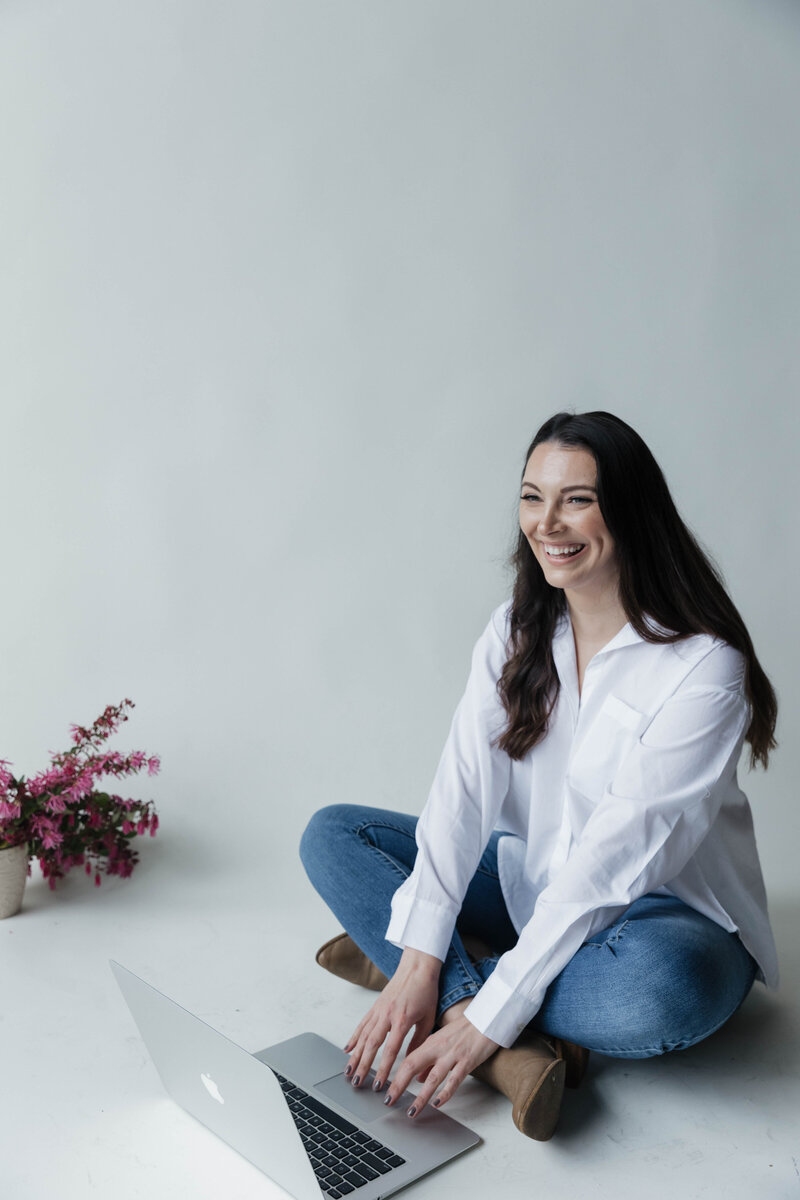 Therapist sitting on floor laughing while holding computer