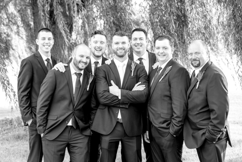A black and white image of groomsmen in front of a willow tree