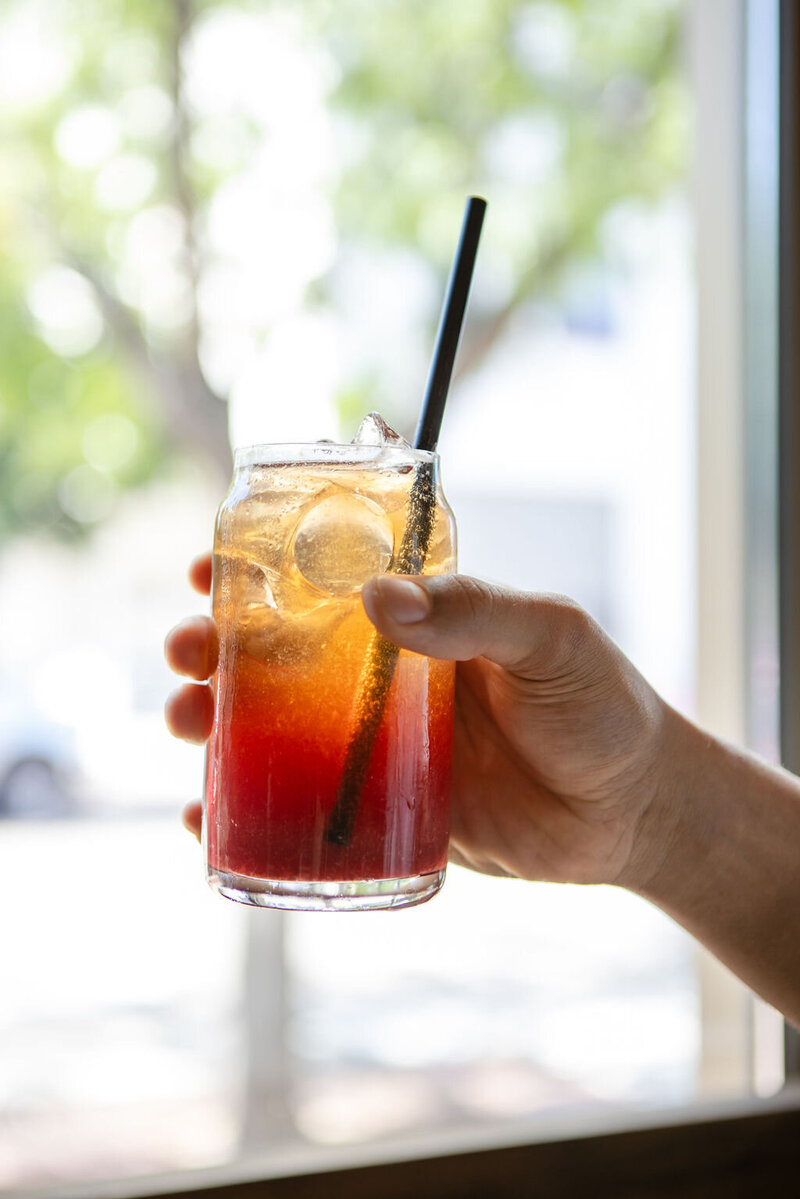 Colorful iced drink held in front of a window