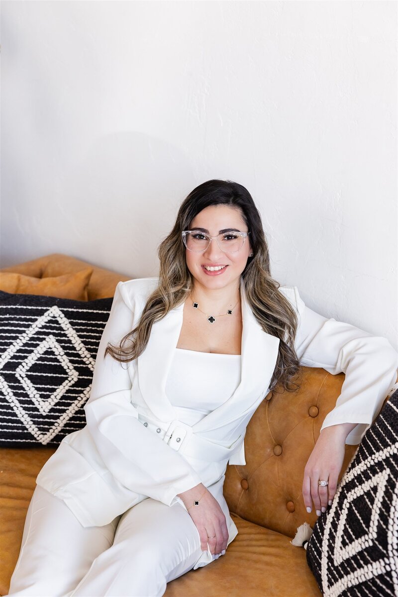 Yudielis Sánchez sentada sonriendo con  un suit blanco.