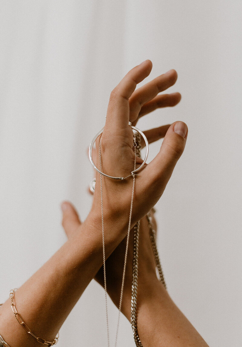 a hand with silver jewelry hanging delicately from it
