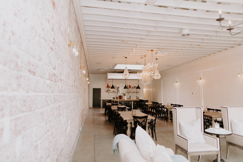 Interior of our studio space with exposed brick wall, lounge furniture, tables and chairs.