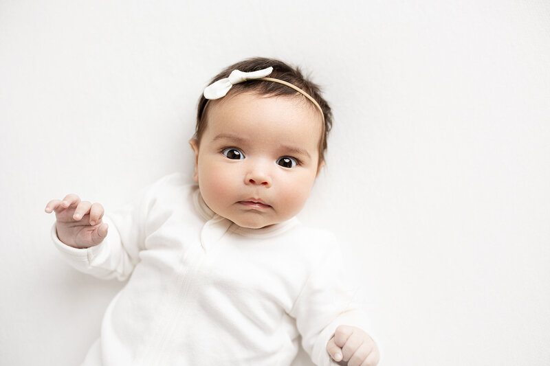 A baby is awake and looking up at a baby photographer in Coquitlam