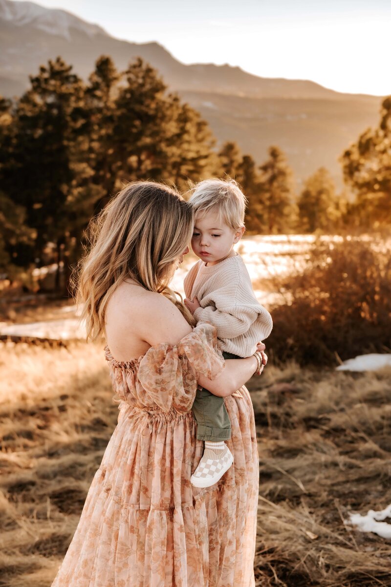 Pregnant mother holding her son with mountains in the background