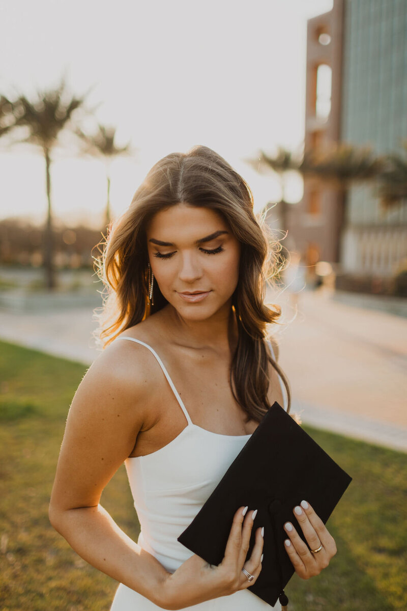 Senior girl holding her cap and looking down