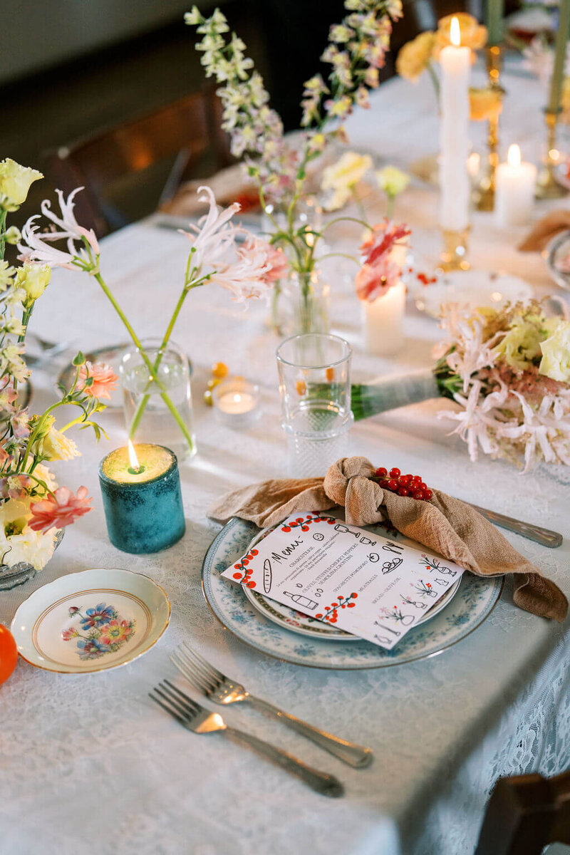 Wedding table decorated with florals, candles and berries on floral plates. Designed by Jessamine floral and event, New Jersey floral designer