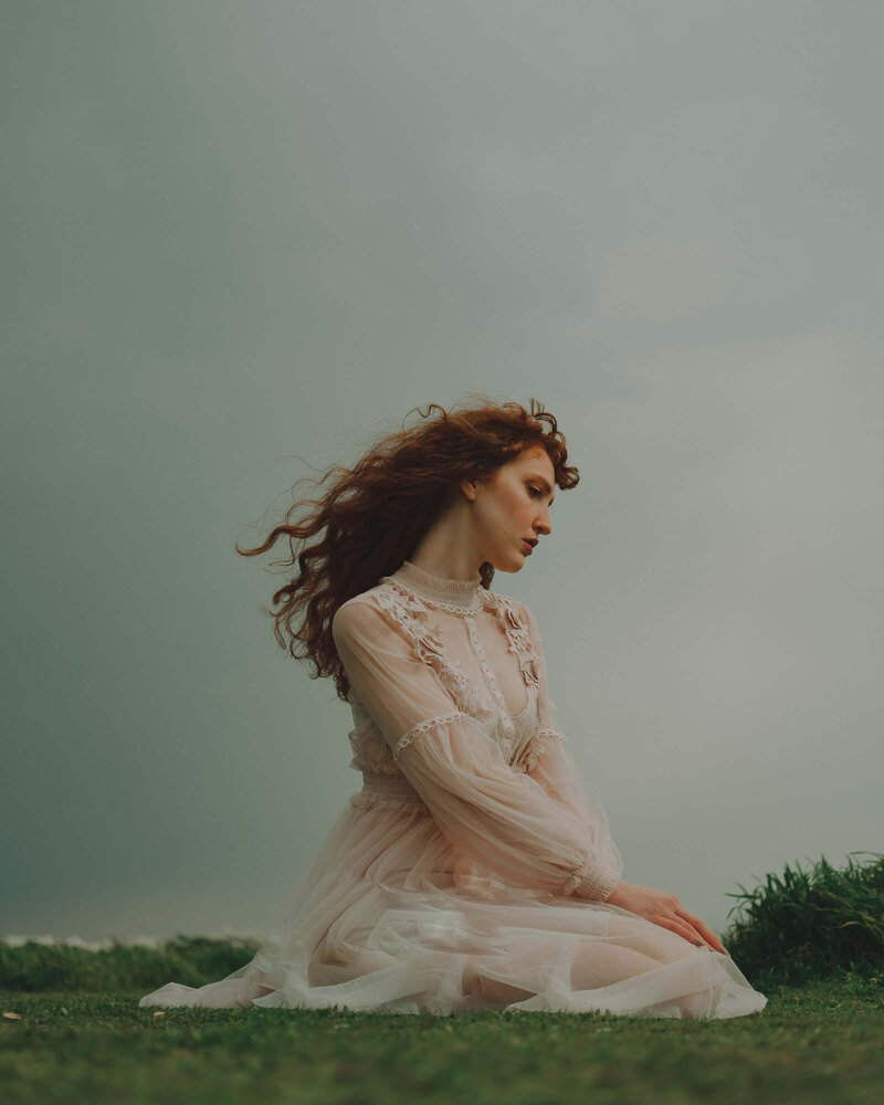 woman wearing a white dress standing in a field with her eyes closed