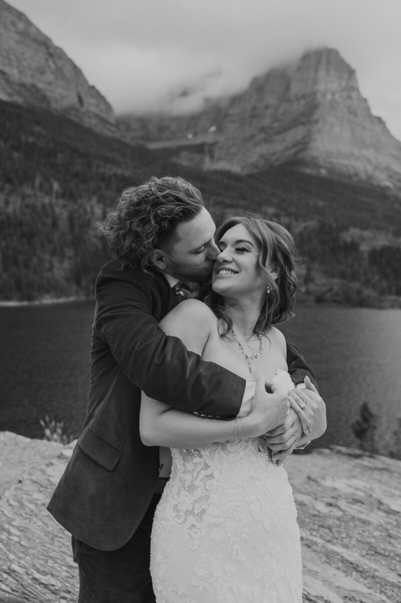 A black and white photo of a couple embracing and looking at each other during their elopement in Glacier National Park.