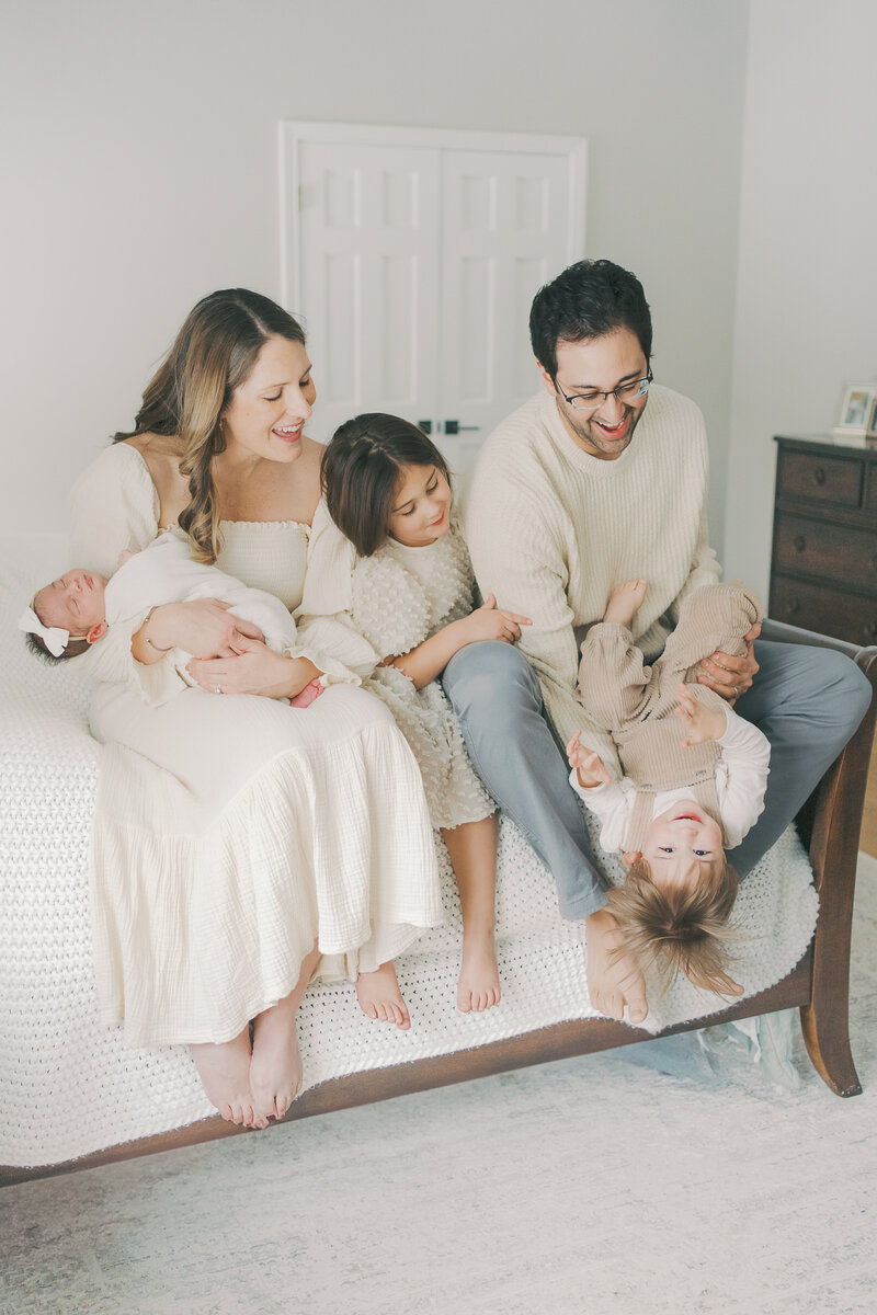 family sitting on bed playing together