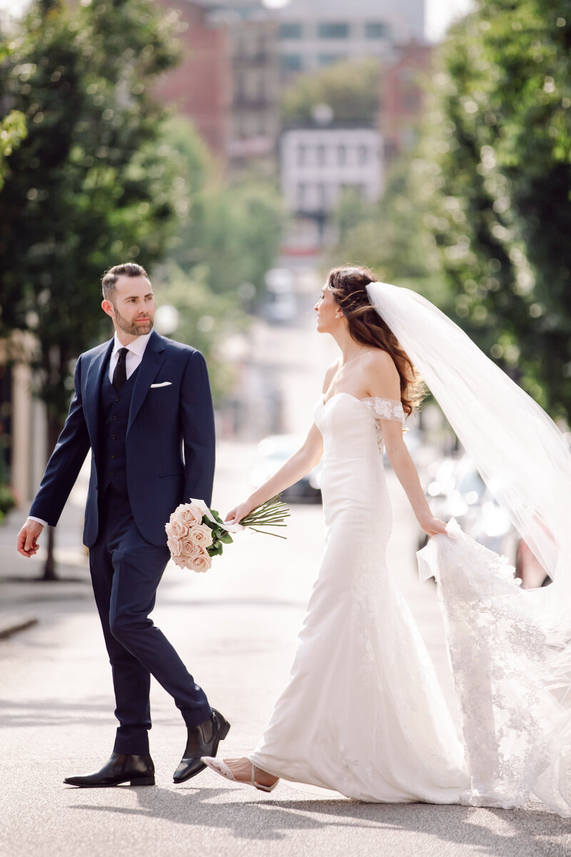 Bride and groom holding hands crossing a street