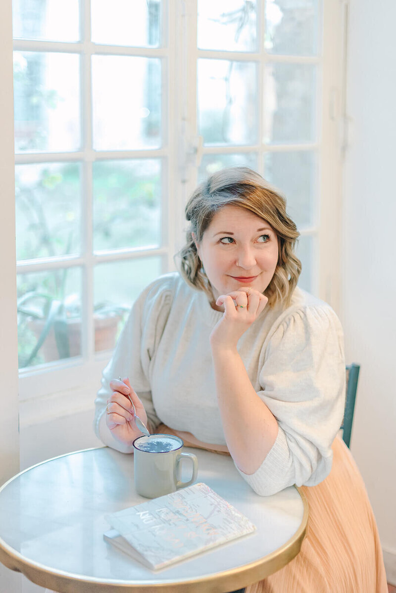 Rachael Laporte, Paris Photographer, sitting at table with drink and notebook