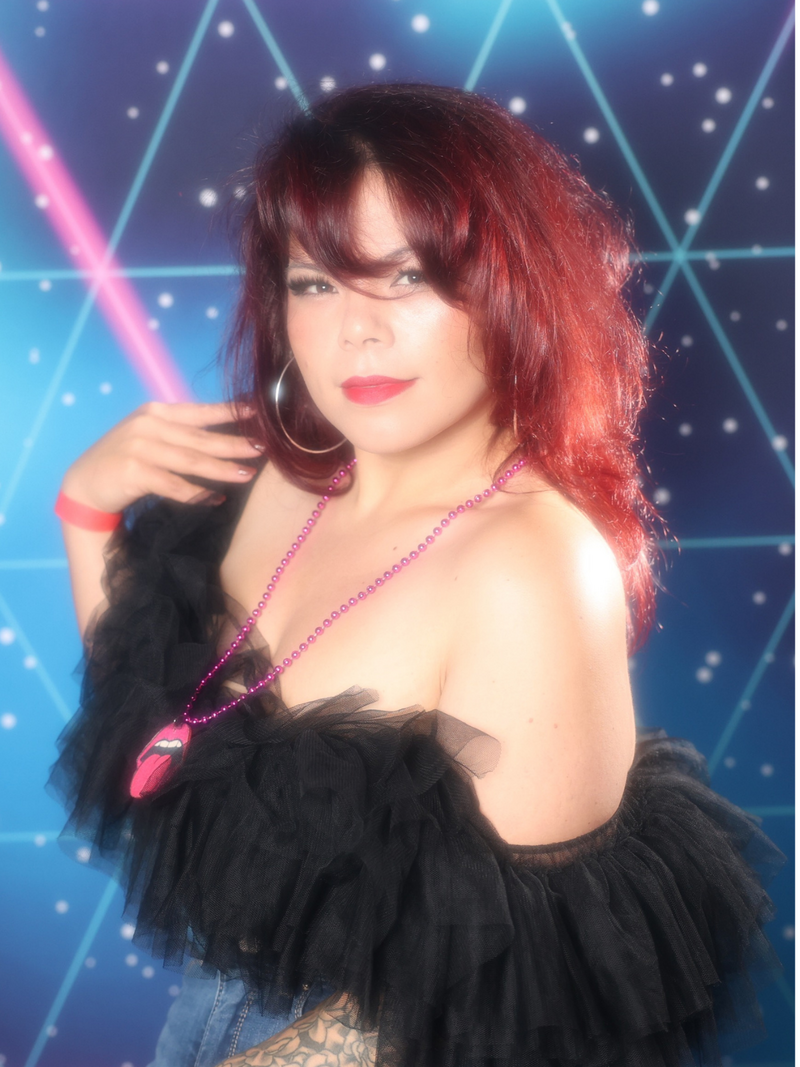 Woman dressed in 80s attire posing in front of a blue and pink 80's backdrop with vintage 80's glamour shots filter, captured by MISGIF’s 80's Glamour Shots photo booth for upscale corporate events in Phoenix, Arizona