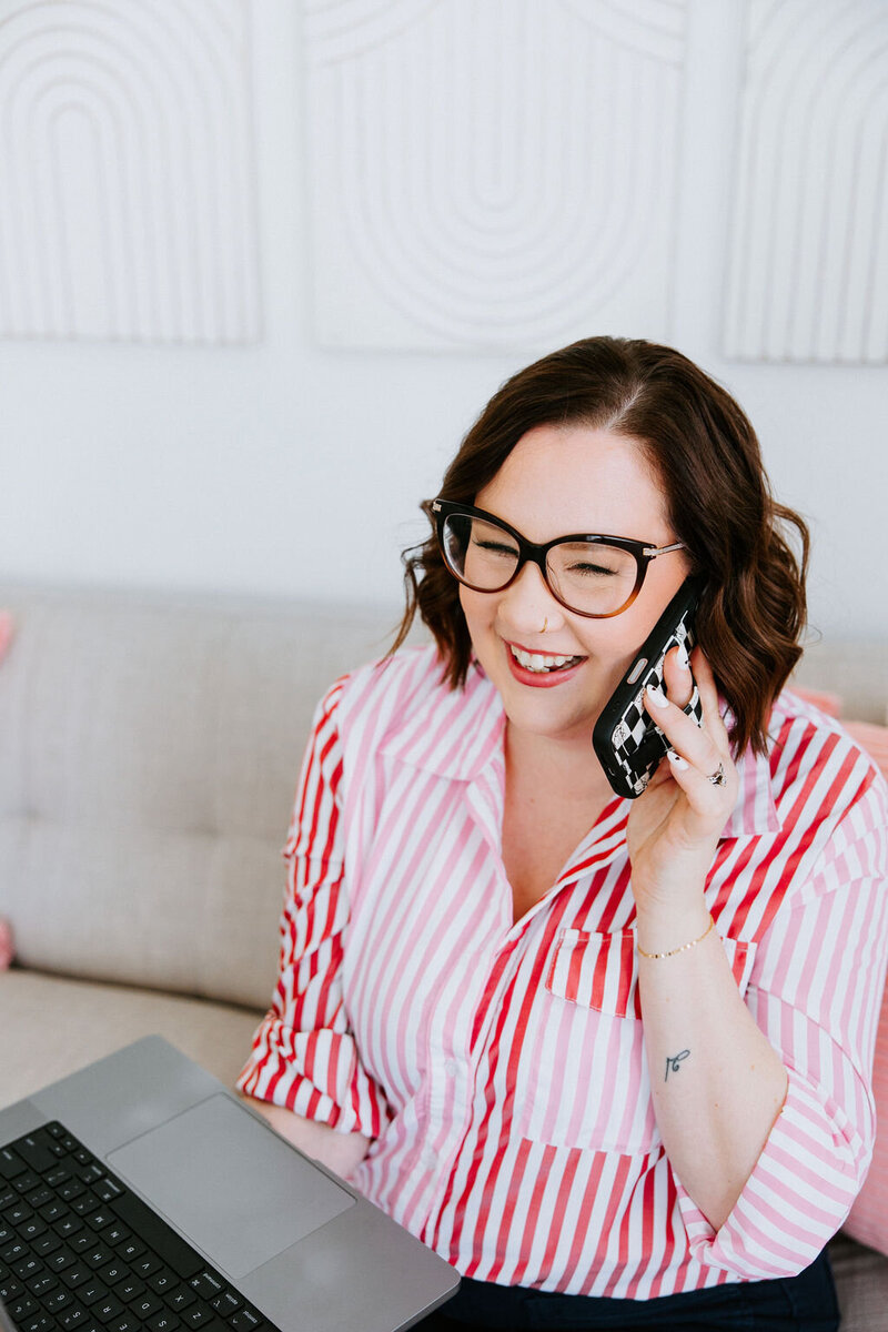 Business coach for photographers Sara Gillis sits on a couch, sending messages on her cell phone