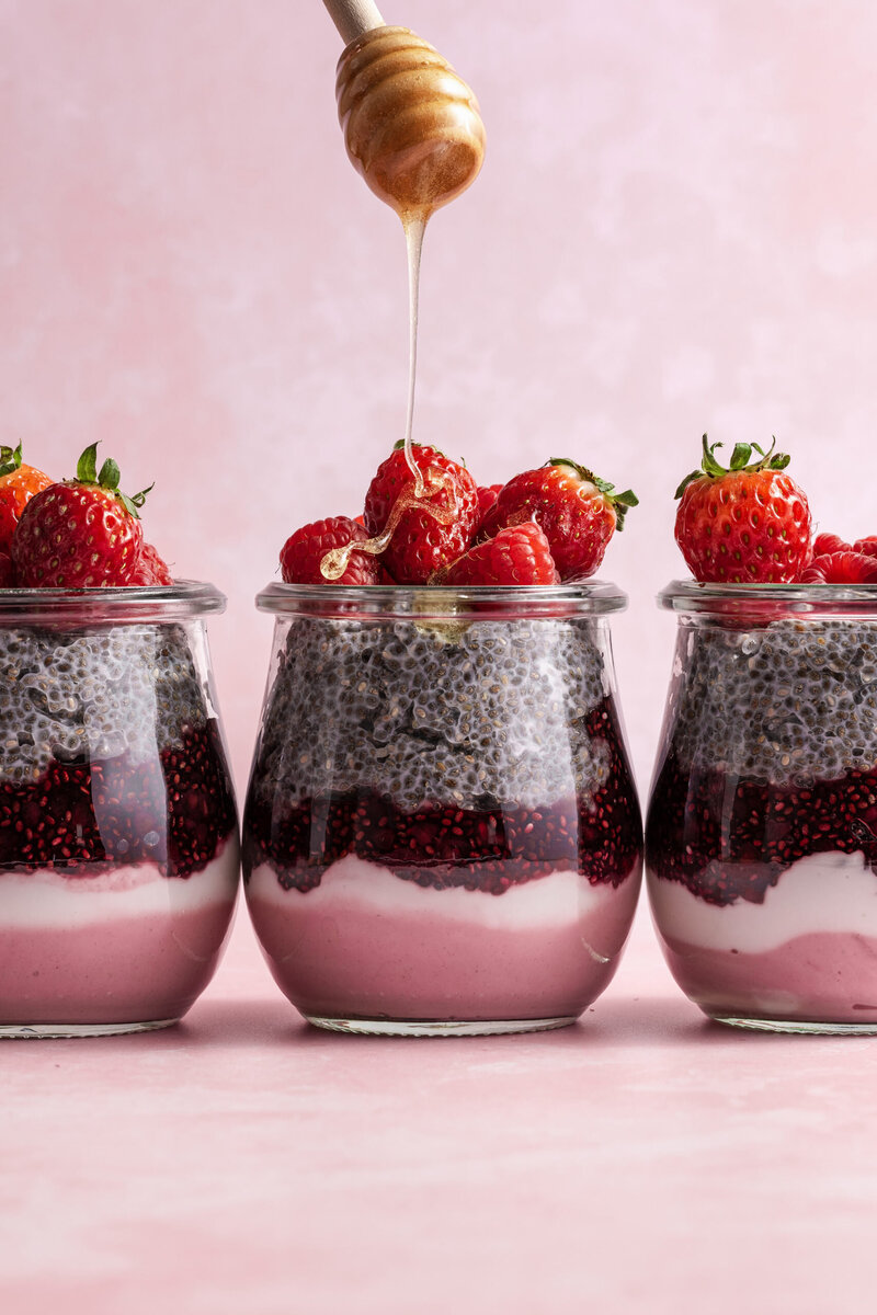 Three glass jars with layers of fruit and chia pudding