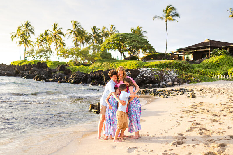 mom and kids snuggle on a white sandy  beach