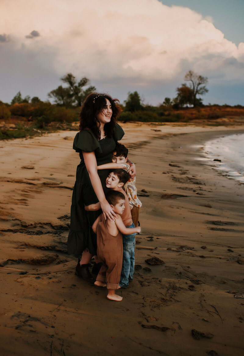A mother holding her three young boys by the water at Grapevine Lake at blue hour.