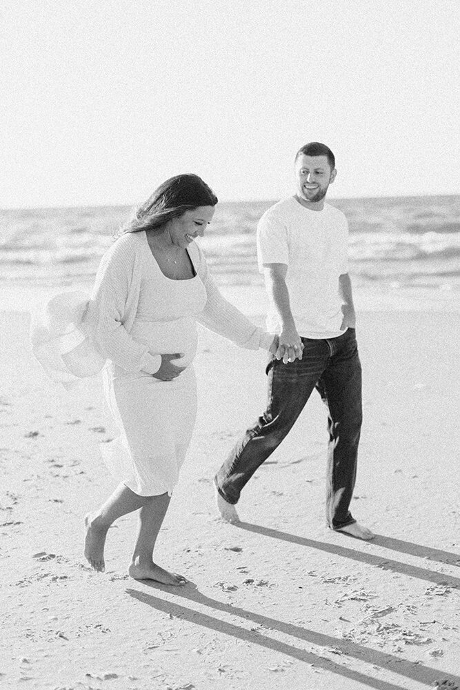 expecting couple walking on beach