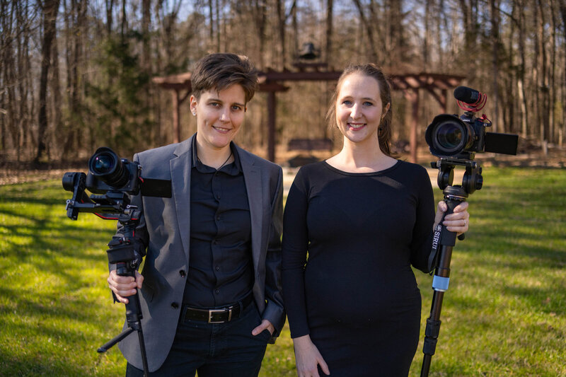 Two people holding cameras smiling together 