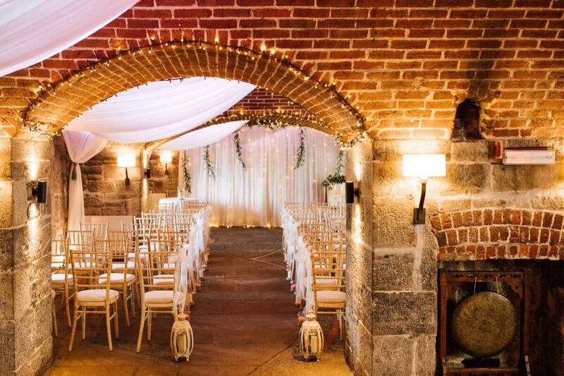 A draped backdrop with rows of chairs set up in front for a wedding ceremony