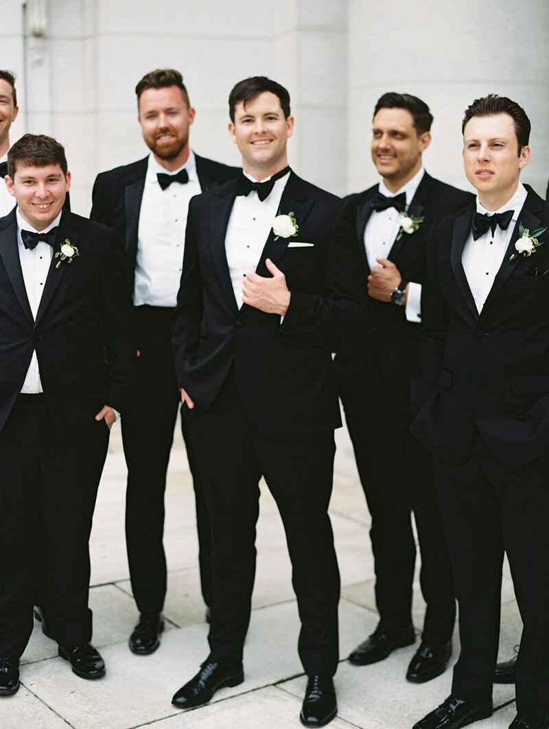 Bride and groom in front of brown door with black tux and Berta wedding gown taken by film photographer chicago Allison Francois
