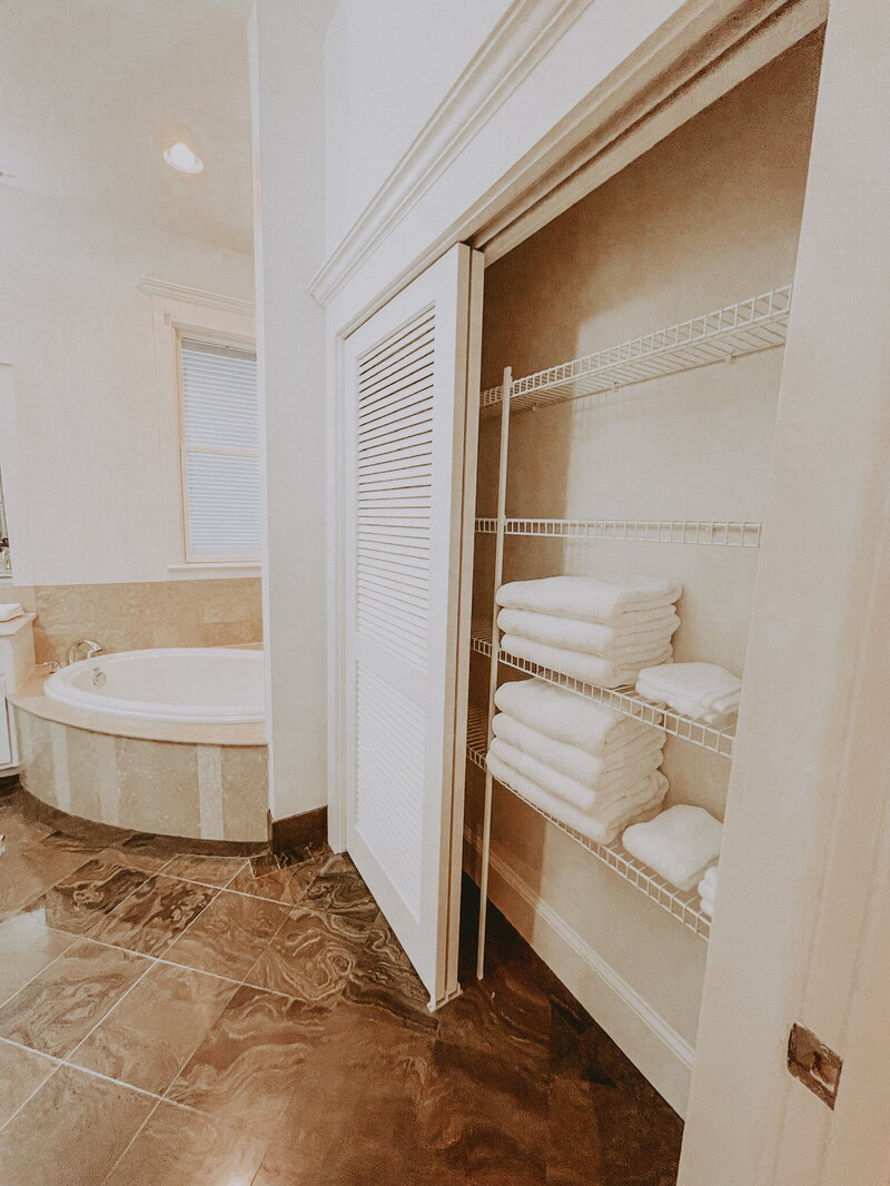 white bathroom with tile floors and a closet with white linens