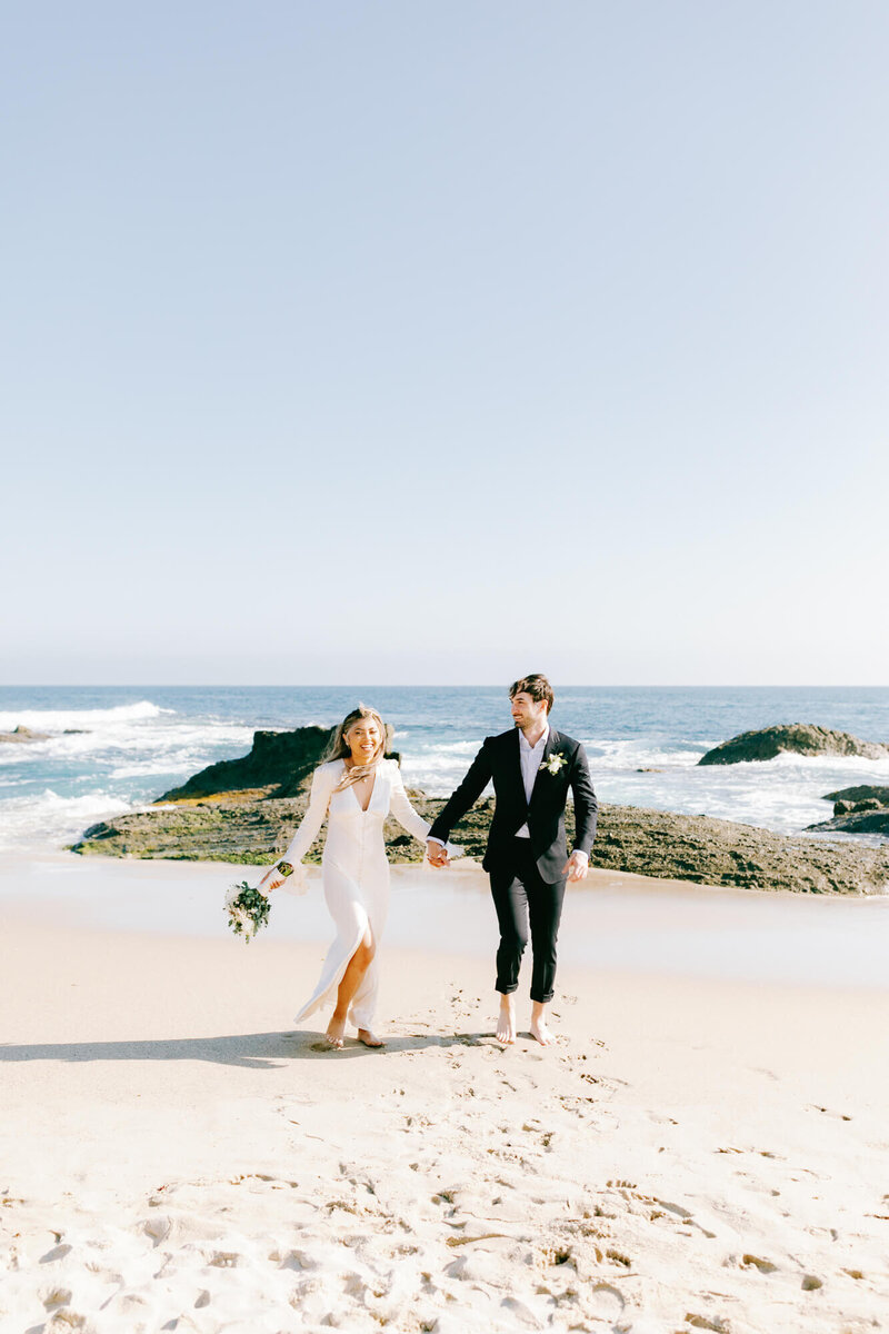 candid photo of bride and groom frolicking on the beach