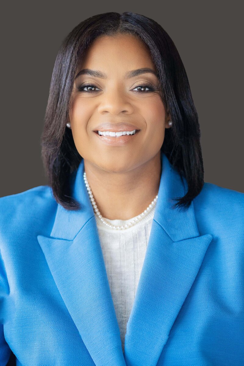 A professional atlanta headshot of a woman wearing a vibrant blue blazer over a white blouse, accessorized with a pearl necklace. 