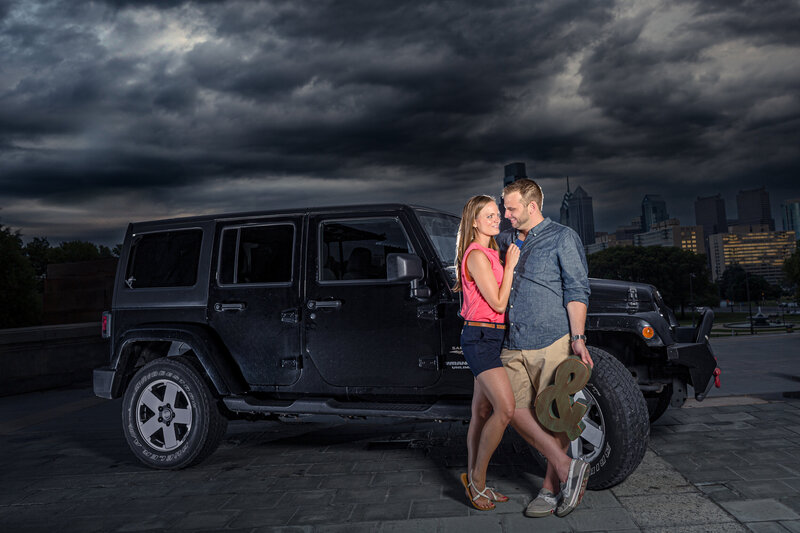 A bold and unique engagement session featuring a couple with their Jeep at the top of the iconic Philadelphia Museum of Art steps, blending adventure and city style.