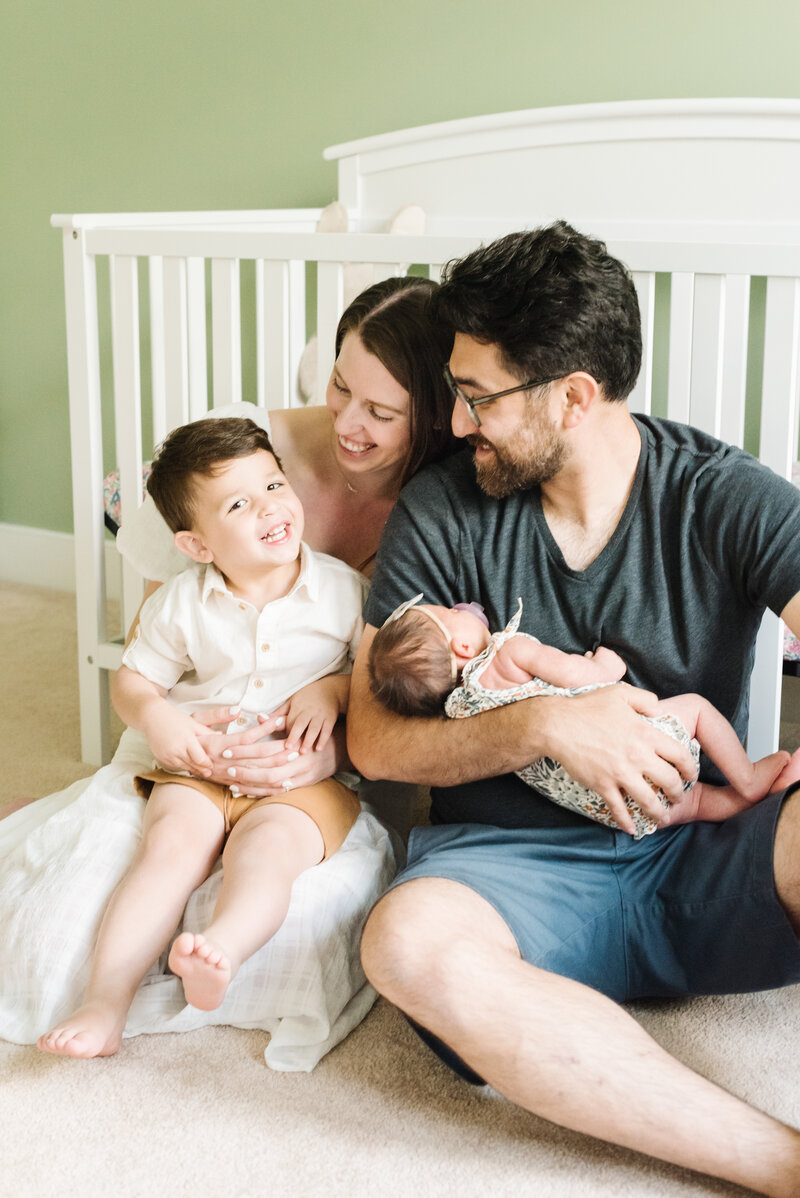 Parents sitting in front of crib with toddler and newborn - Washington DC Newborn Photographer